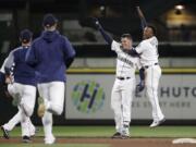 Seattle Mariners players rush onto the field to greet Ryon Healy, second right, as Jean Segura jumps on him after Healy's game winning, 1-run single against the Los Angeles Angels in the 11th inning of a baseball game Saturday, May 5, 2018, in Seattle. The Mariners won 9-8.