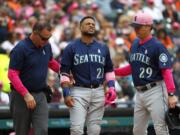 Seattle Mariners' Robinson Cano (22) grimaces while being attended to by trainer Rob Nodine, left, and manager Scott Servais (29) after being hit in the hand by a Detroit Tigers' Blaine Hardy pitch in the third inning of a baseball game in Detroit, Sunday, May 13, 2018. Cano left the game.