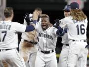 Seattle Mariners' Guillermo Heredia, center, is cheered by teammates after hitting a one-run single to beat the Texas Rangers in the 11th inning of a baseball game Tuesday, May 15, 2018, in Seattle. The Mariners won 9-8.