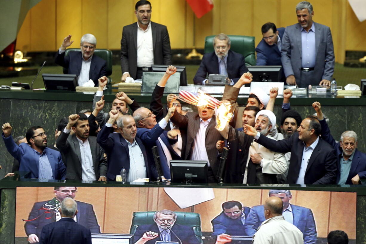 Iranian lawmakers burn pieces of paper representing the U.S. flag and the nuclear deal as they chant slogans against the U.S. on Wednesday at the parliament in Tehran, Iran.