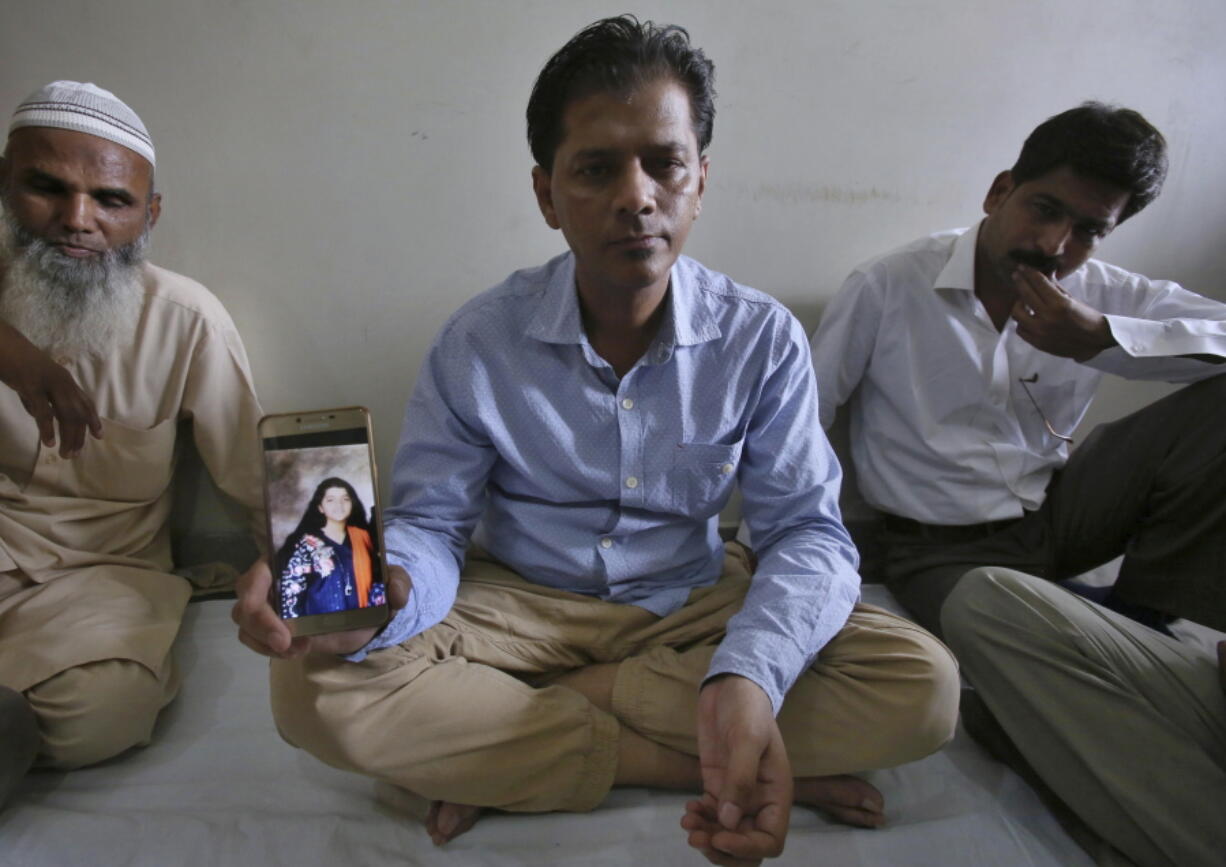 Abdul Aziz Sheikh, center, father of Sabika Sheikh, a victim of a shooting at a Texas high school, shows a picture of his daughter in Karachi, Pakistan, Saturday, May 19, 2018. The Pakistani foreign exchange student is among those killed in the shooting, according to a leader at a program for foreign exchange students and the Pakistani Embassy in Washington, D.C. Megan Lysaght, manager of the Kennedy-Lugar Youth Exchange & Study Abroad program (YES), sent a letter to students in the program confirming that Sabika Sheikh was killed in the shooting.