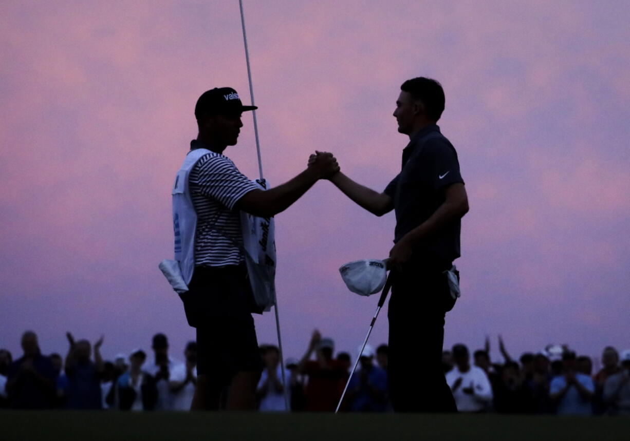 Caddie Brian Dilley, left, congratulates Aaron Wise after Wise won the AT&T Byron Nelson golf tournament in Dallas, Sunday, May 20, 2018.