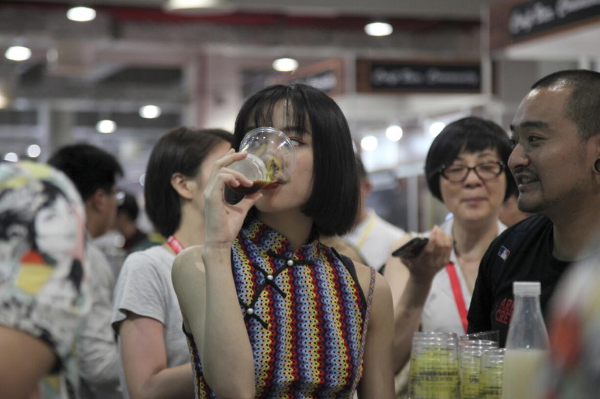 A woman drinks beer at the 2018 Craft Beer of China Exhibition in Shanghai.