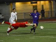 Columbia River forward Jake Connop (right) lunges for a loose ball while Franklin Pierce goalkeeper Noah Carver dives in the first half of the 2A state semifinal at Sumner High School on Friday, May 25, 2018.