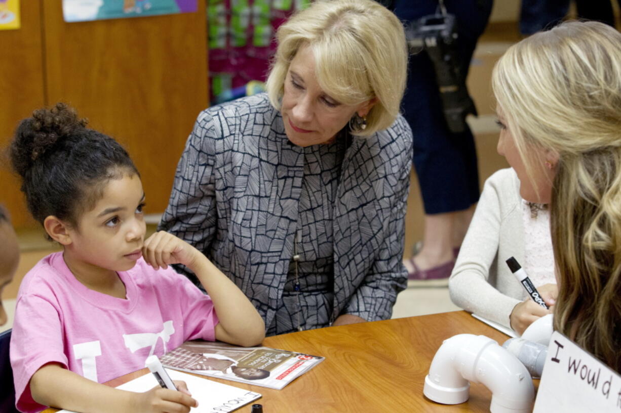 Education Secretary Betsy DeVos accompanied by first grade teacher Alexandra Lyons speaks to student Ayana Greene, during a visit of the Federal School Safety Commission at Hebron Harman Elementary School in Hanover, Md., on Thursday. DeVos listened to first-graders share stories about friendship during a field trip by a presidential commission seeking ways to stem a steady stream of school violence. The school specializes in mentoring and counseling as opposed to punitive discipline.