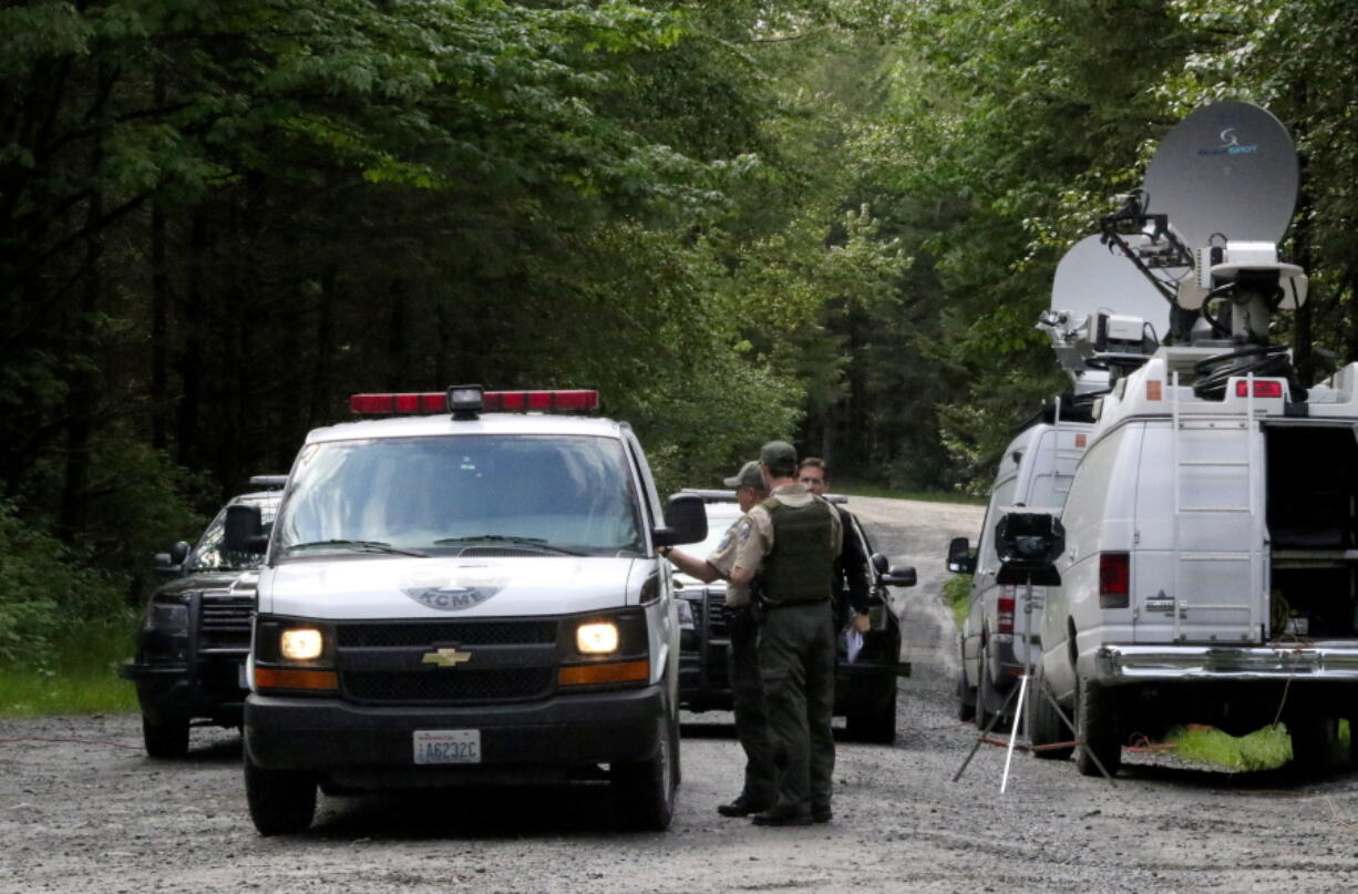 Washington State Fish and Wildlife Police confer with an individual from the King County Medical Examiner’s office on a remote gravel road above Snoqualmie,, following a fatal cougar attack Saturday. One man was killed and another seriously injured when they encountered a cougar Saturday while mountain biking in Washington state, officials said.