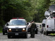 Washington State Fish and Wildlife Police confer with an individual from the King County Medical Examiner’s office on a remote gravel road above Snoqualmie,, following a fatal cougar attack Saturday. One man was killed and another seriously injured when they encountered a cougar Saturday while mountain biking in Washington state, officials said.