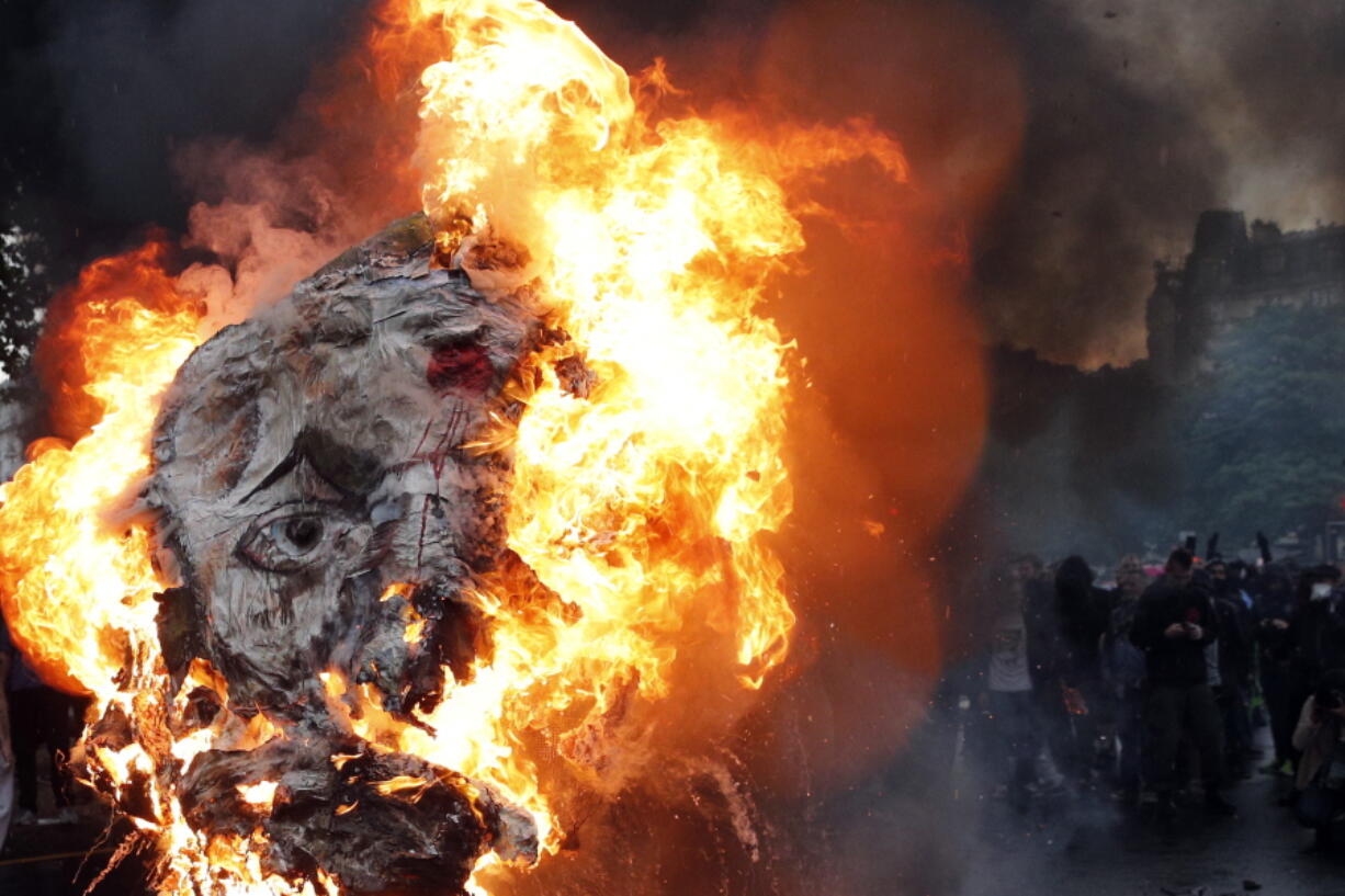 A giant mask depicting French President Emmanuel Macron is burned during a demonstration in Paris on May 22. French public services workers have gone on strike as part of their protest a government plan to cut 120,000 jobs by 2022.