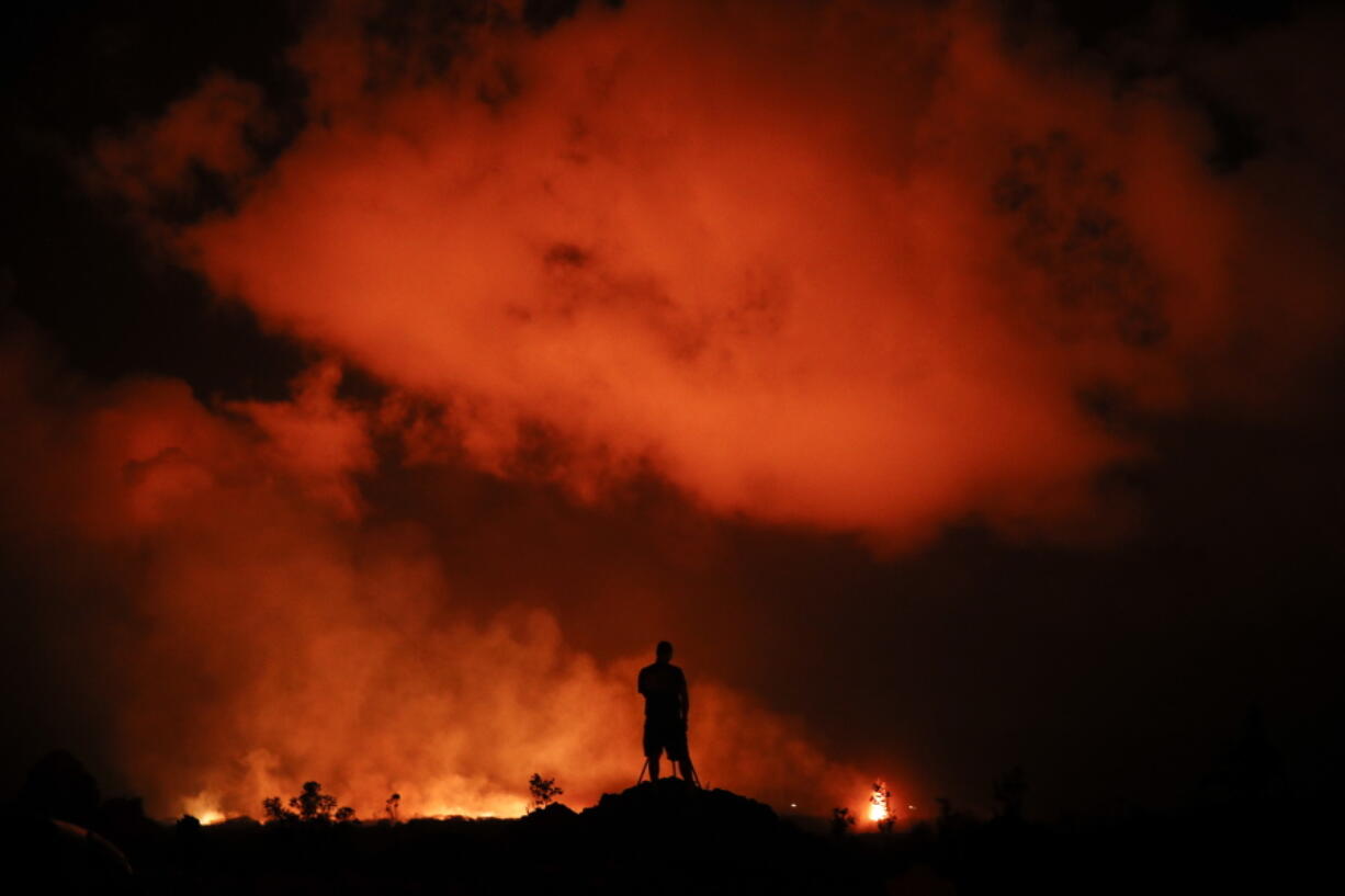 Peter Vance, 24, photographs lava erupting in the Leilani Estates subdivision near Pahoa, Hawaii Friday, May 18, 2018. Hawaii residents covered their faces with masks after a volcano menacing the Big Island for weeks exploded, sending a mixture of pulverized rock, glass and crystal into the air in its strongest eruption of sandlike ash in days. (AP Photo/Jae C.