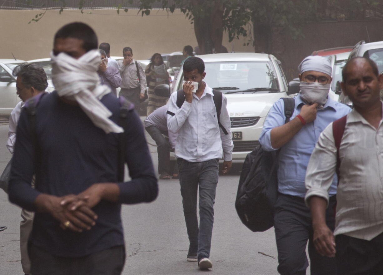 People cover their noses as a dust storm envelops the city in New Delhi, India. A powerful dust storm and rain swept parts of north and western India overnight, causing house collapses, toppling trees and leaving dozens dead and more than 160 injured, officials said Thursday.