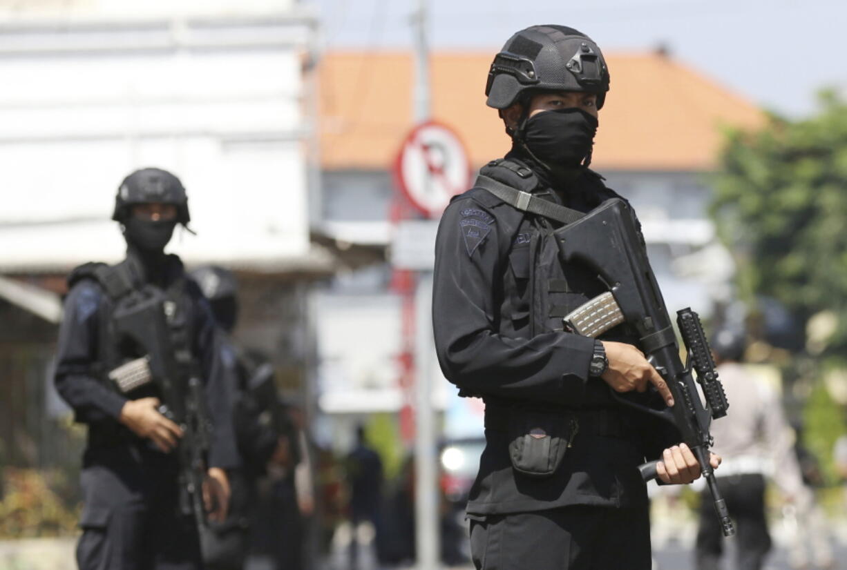 Officer stand guard outside the local police headquarters following an attack in Surabaya, East Java, Indonesia, on Monday. The police headquarters in Indonesia’s second largest city was attacked Monday by suspected militants who detonated explosives from a motorcycle, a day after suicide bombings at three churches in the city by members of one family killed a number of people.