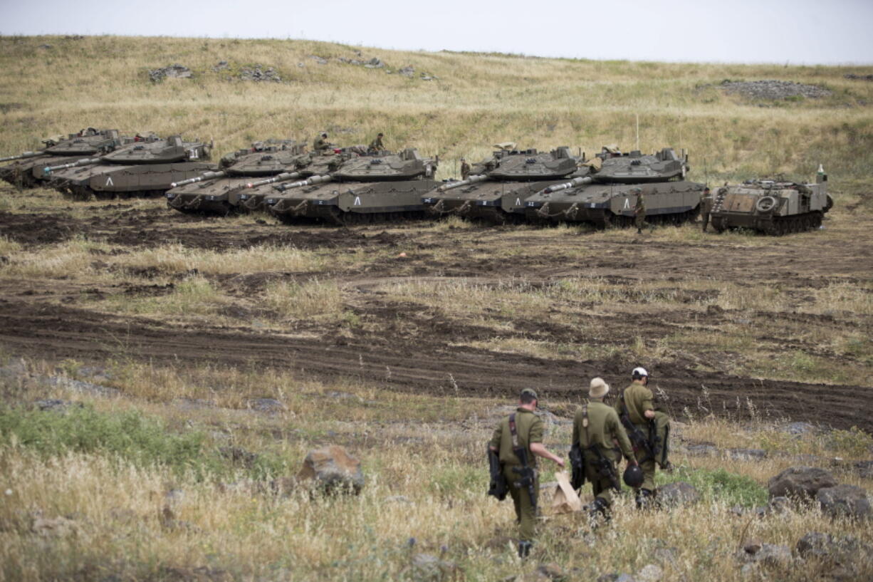 Israeli soldiers walk past tanks in the Israeli-controlled Golan Heights, near the border with Syria, Thursday, May 10, 2018. Israel says it struck dozens of Iranian targets in Syria overnight in response to a rocket barrage on Israeli positions in the Golan Heights. It was the biggest Israeli strike in Syria since the 1973 war.