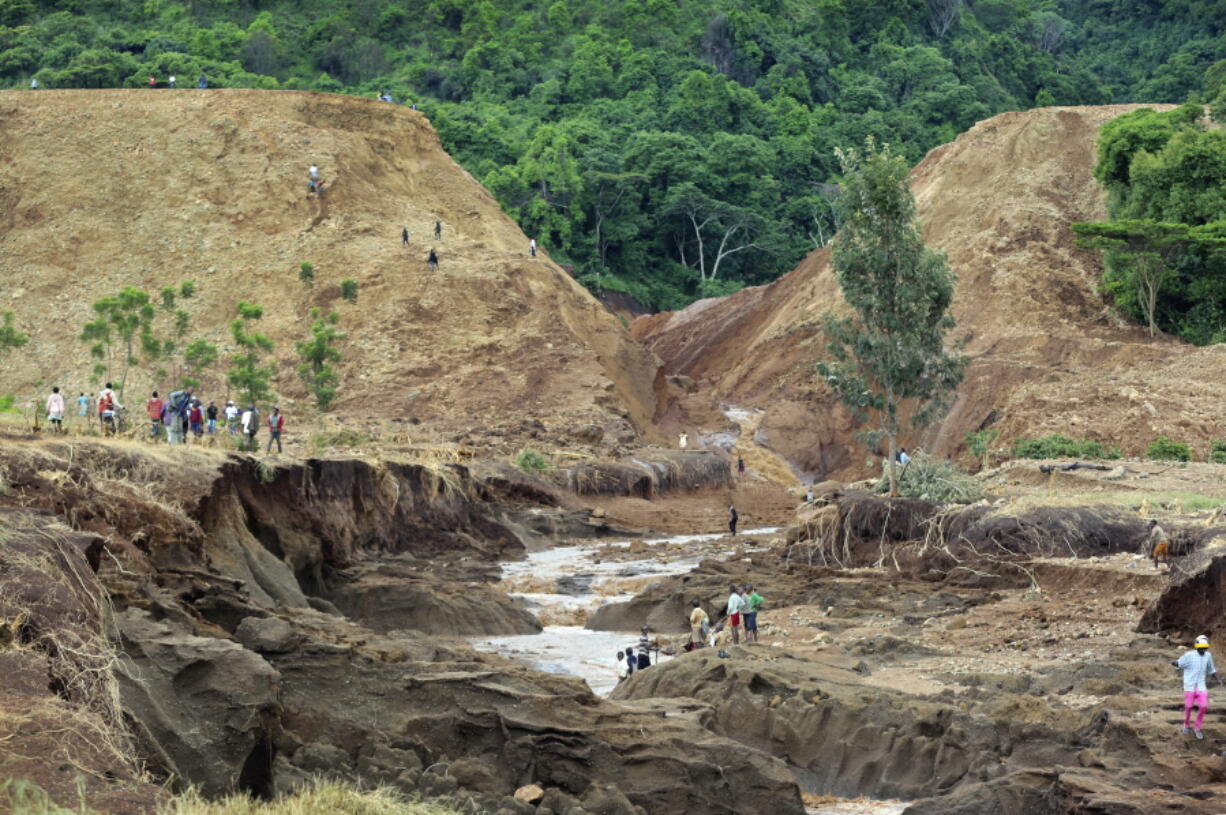 People gather in front of the broken banks of the Patel dam near Solai, in Kenya’s Rift Valley, Thursday, May 10, 2018. A dam burst its banks in Kenya’s Rift Valley, killing at least 41 people and forcing hundreds from their homes, officials said Thursday. At least 20 of the dead were children, police said.