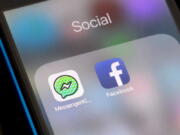 FILE- In this Feb. 16, 2018, file photo, Facebook and Facebook’s Messenger Kids app icons are displayed on an iPhone in New York. Facebook is adding a “sleep” mode to its Messenger Kids service so parents can limit how much time children spend on it.