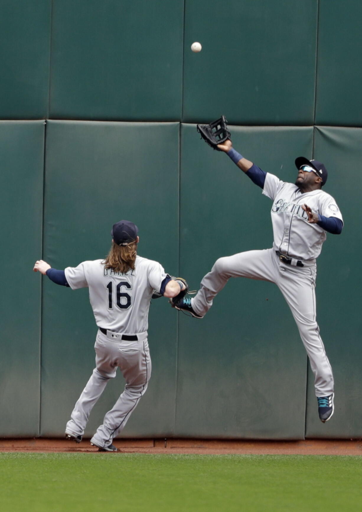 Seattle Mariners center fielder Guillermo Heredia, right, leaps but can’t catch a line drive from Oakland Athletics’ Stephen Piscotty during the first inning of a baseball game Thursday, May 24, 2018, in Oakland, Calif. Piscotty drove in two runs with a double on the play.