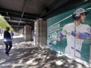 A man walks past an oversized photo of Seattle Mariners second baseman Robinson Cano outside the stadium before the team’s baseball game against the Texas Rangers on Tuesday, May 15, 2018, in Seattle. Cano was suspended 80 games for violating baseball’s joint drug agreement.