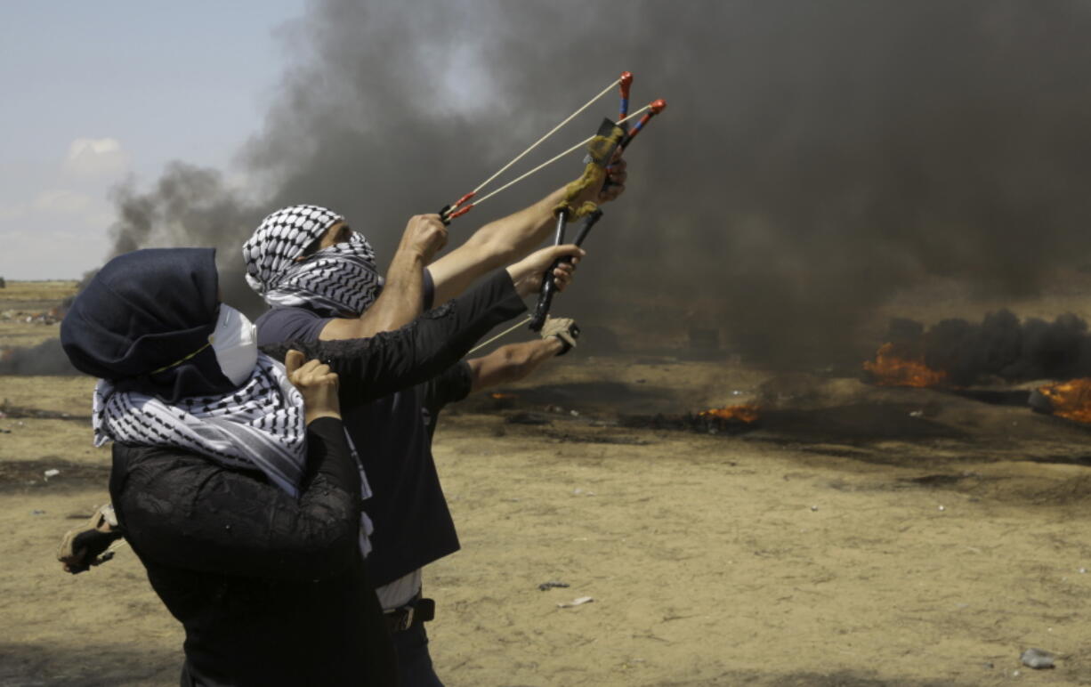 Palestinian protesters hurl stones at Israeli solders as others burn tires near the fence during a protest Friday at the Gaza Strip’s border with Israel.