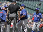 Texas Rangers starting pitcher Bartolo Colon, second from right, smiles as he returns to the mound after talking with a Rangers’ trainer after Colon was hit by a ball hit by Seattle Mariners shortstop Jean Segura during the fourth inning of a baseball game, Wednesday, May 16, 2018, in Seattle. (AP Photo/Ted S.