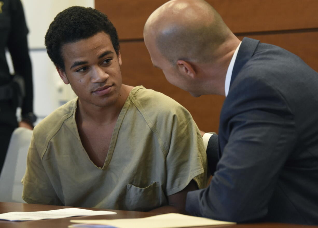 FILE - In this May 3, 2018, file photo, Zachary Cruz, left, speaks to his attorney Mark S. Lowry, before a hearing on a probation violation in Fort Lauderdale, Fla. Cruz, the brother of Florida school shooting suspect Nikolas Cruz, is asking a judge to allow him to move to Virginia where a full-time job awaits him. The motion says Zachary Cruz would be hired as a maintenance mechanic paying $13 an hour. His job and living quarters would be provided by Nexus Services, which the motion says specializes in helping people adjust after prison or treatment.