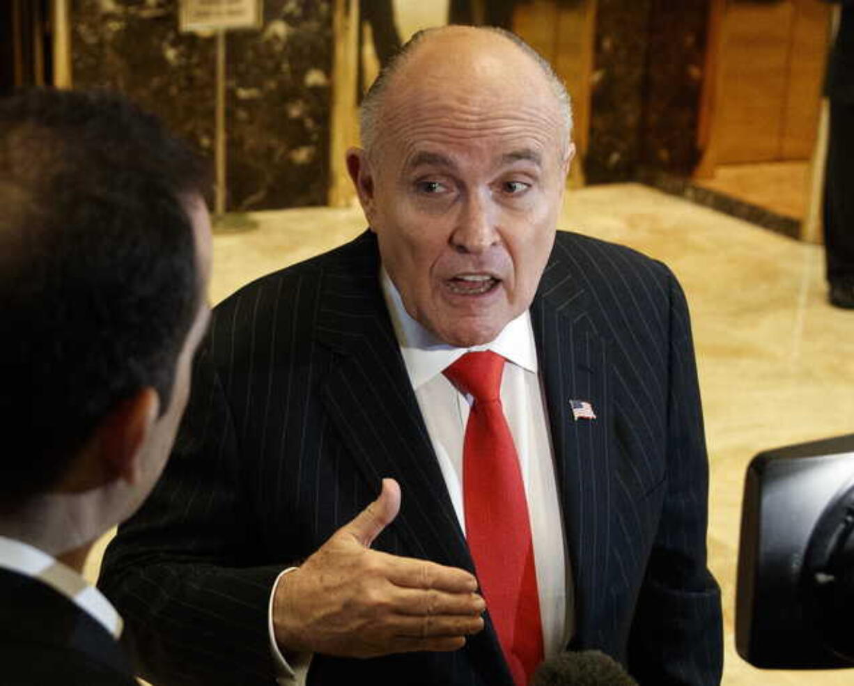 In this Jan. 12, 2017, file photo, former New York City Mayor Rudy Giuliani talks with reporters in the lobby of Trump Tower in New York. Giuliani's revelation that U.S. President Donald Trump reimbursed his personal attorney for a $130,000 payment to a porn star to keep her quiet about an alleged affair is raising new legal questions, including whether the president and his campaign violated campaign finance laws.