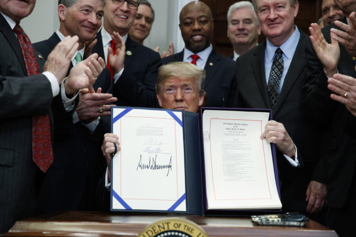 President Donald Trump shows off the “Economic Growth, Regulatory Relief, and Consumer Protection Act,” in the Roosevelt Room of the White House on Thursday in Washington.