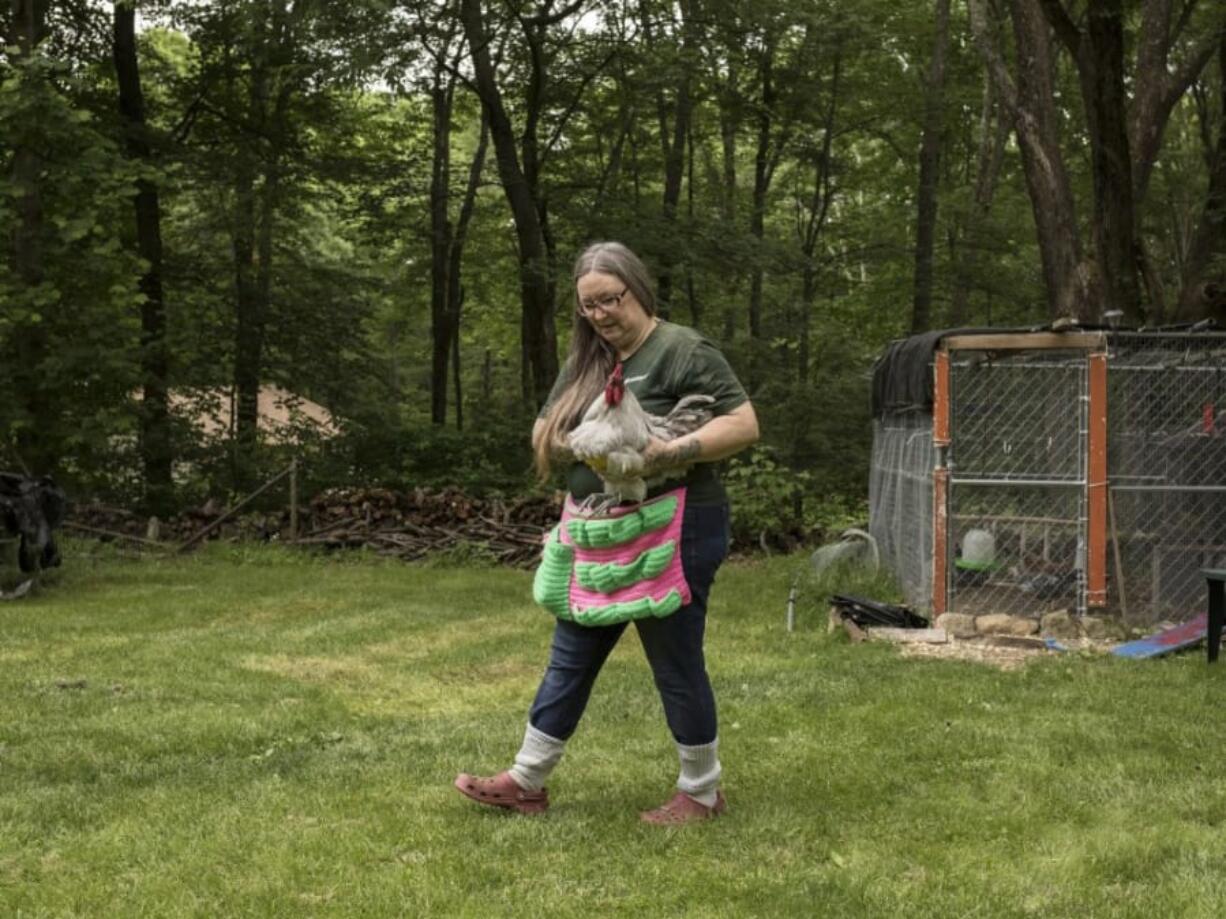 Crystal Cahill leaves a chicken coop behind her home in Great Meadows, N.J., with a rooster in her arms.