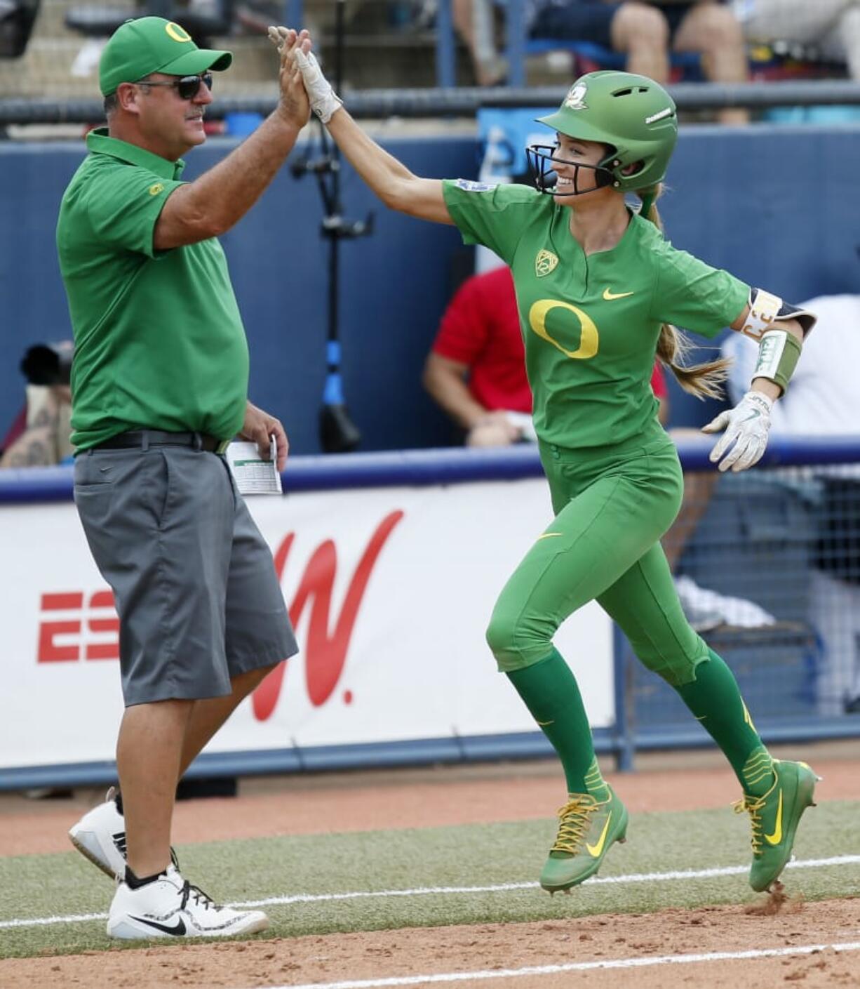 Oregon’s Haley Cruse (26) high-fives coach Mike White after hitting a two-run home run against Arizona State in the bottom of the fifth inning during the first game of the NCAA softball Women’s College World Series, in Oklahoma City, Thursday, May 31, 2018.