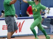 Oregon’s Haley Cruse (26) high-fives coach Mike White after hitting a two-run home run against Arizona State in the bottom of the fifth inning during the first game of the NCAA softball Women’s College World Series, in Oklahoma City, Thursday, May 31, 2018.