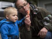 Rick Brown shows his grandson how to blow bubbles outside Tabor’s home in Kalama.