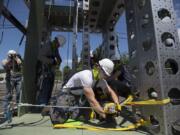 Student Justin Spencer, center in white, performs a simulated rescue while on a wind turbine training tower at the Northwest Renewable Energy Institute. Safety is a focus of student training.