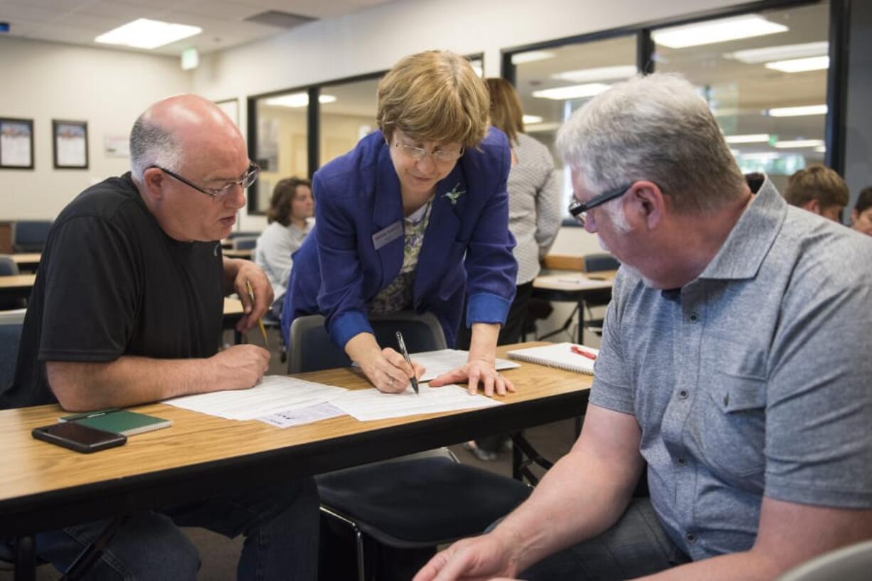 WorkSource employment specialist Pam Noll, center, works with Vince Cone, left, and Norm Lackey during a job search. The two former Georgia-Pacific workers are among nearly 300 who have been laid off at the paper mill since the start of May.