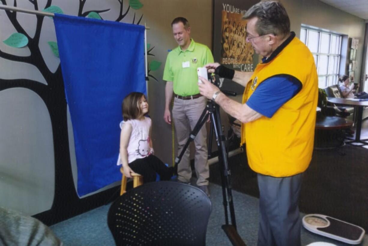 Orchards: Harper Martin, 4, has her picture taken by Jim Terrell as part of the Orchards Lions Club’s annual identification project, in which they create ID cards for kids.