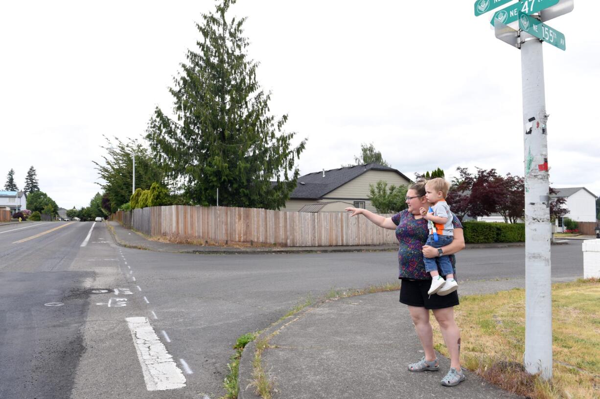 Heather Sinnott, chairwoman of the Burnt Bridge Creek Neighborhood Association, stands with her 2-year-old son, Henry, as she points to the intersection near her home on Northeast Poplar Street where the neighborhood association is hoping to paint a mural to slow down traffic. The speed limit where Poplar Street turns into Northeast 47th Street is 25 mph, but Sinnott says many drivers far exceed this speed and that it is dangerous for the neighborhood.