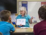 Julie Ward, a paraeducator at Woodburn Elementary School in Camas, helps students learn to read on Thursday. She spends about 25 percent of her days helping students with reading and 75 percent working with students on mathematics.