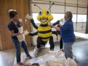 Shirley Stowell, left, and Barbara Rowe discuss the engineering required to lift this large, somewhat fragile bee and install it atop Battle Ground’s Rose Festival Parade float. It may all seem a little silly, Stowell said, but when the finished float heads for Portland she always gets goosebumps about a job well done.