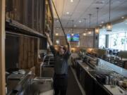 Grays server Aaron Snoddy of Battle Ground opens up the bar area at the restaurant, located at the Hilton Vancouver Washington. The restaurant is finishing up a $1.7 million redesign.