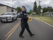 Officer Jason Nicholson puts up crime scene tape at the intersection of Northeast 114th Street and Northeast 124th Avenue after an officer-involved shooting in Brush Prairie on Wednesday afternoon, June 13, 2018. The tape was removed soon after and the intersection was opened.