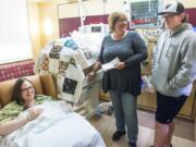 Karrie Keehart, from left, Mary Hylton and Jake Hylton react to a letter written by Jake at the PeaceHealth Southwest Medical Center neonatal intensive care unit in Vancouver. Jake was a premature baby at the hospital 14 years ago, and as part of a class project, he printed 46 letters detailing what the experience was like for his mother when he was born prematurely.