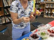 Orchards: Marty Fields, a nutrition educator with Washington State University Extension’s Supplemental Nutrition Assistance Program Education, handed out fruit kabobs to guests at Silver Star Elementary School’s Family Art Show.