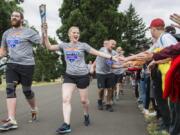 Special Olympics athlete Danny Williamson, from left, and Tracie Mathews of the Houston Police Department high-five students from an Oregon Museum of Science and Industry summer camp while carrying the Special Olympics Flame of Hope along Discovery Trail during the Law Enforcement Torch Run final leg that ended at the Fort Vancouver National Historic Site on Thursday morning. Williamson said his involvement with the games has given him life-changing opportunities, like playing flag football at Gillette Stadium, the home of the New England Patriots.