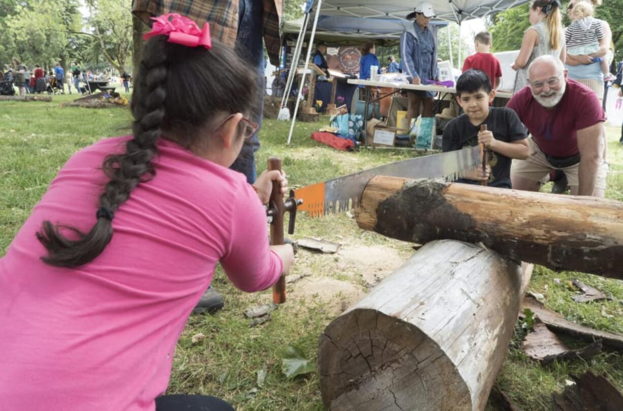 Valerie Rodriguez, left, and Jonathan Rodriguez, cut a log with volunteer Jeff Booth at the 2016 National Get Outdoors Day at the Fort Vancouver National Historic Site.