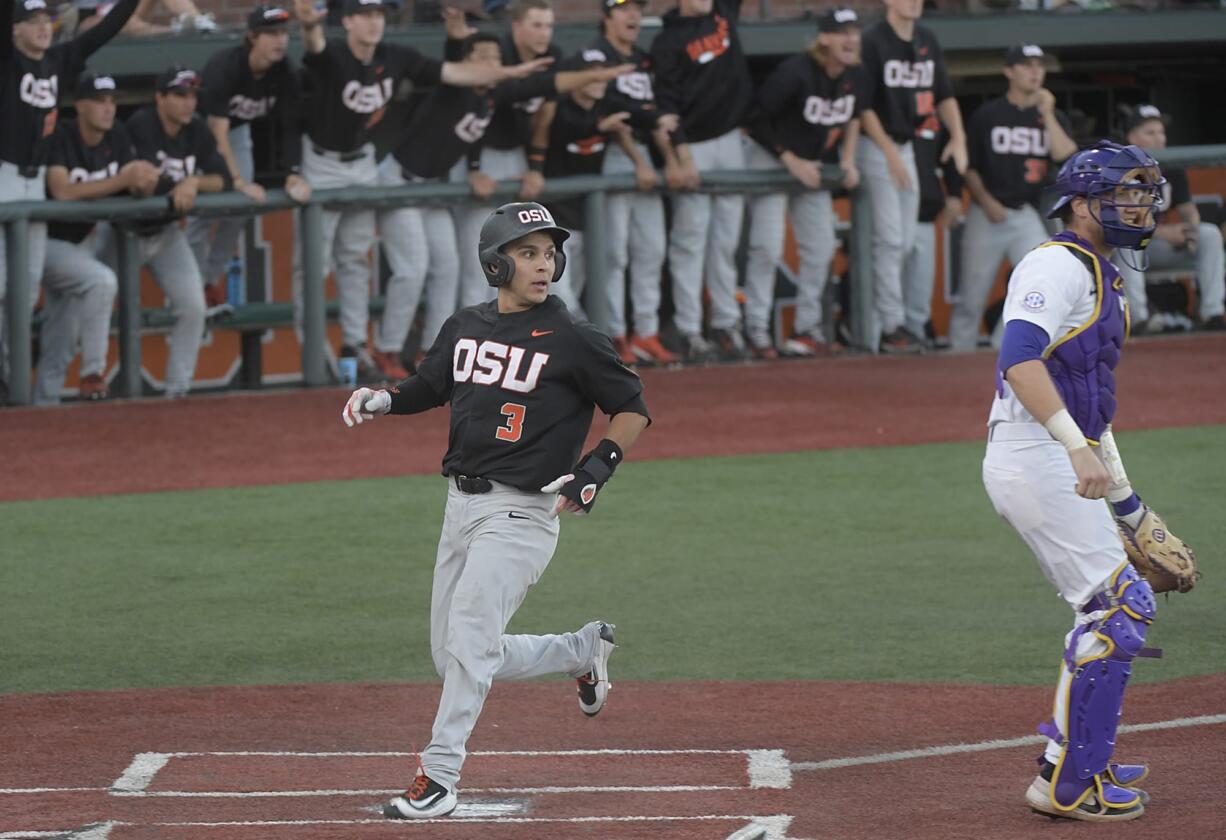 Oregon State's Nick Madrigal scores as LSU catcher Nick Coomes stands in front of the plate during an NCAA college baseball tournament regional game in Corvallis, Ore., Saturday, June 2, 2018.