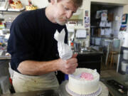 FILE - In this March 10, 2014, file photo, Masterpiece Cakeshop owner Jack Phillips decorates a cake inside his store in Lakewood, Colo. The Supreme Court is setting aside a Colorado court ruling against a baker who wouldn’t make a wedding cake for a same-sex couple. But the court is not deciding the big issue in the case, whether a business can refuse to serve gay and lesbian people.