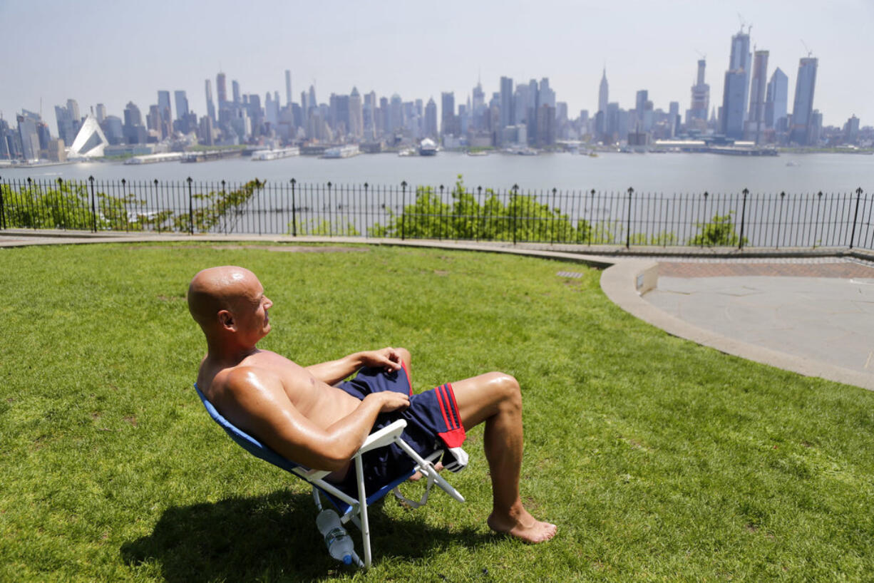 FILE - In this Tuesday, May 15, 2018 file photo, Rick Stewart sits in the sunshine with the New York City skyline in the background, in a park in Weehawken, N.J. According to weather records released on Wednesday, June 6, 2018, May reached a record 65.4 degrees in the continental United States, which is 5.2 degrees above the 20th century average.