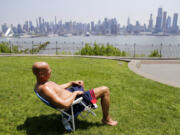 FILE - In this Tuesday, May 15, 2018 file photo, Rick Stewart sits in the sunshine with the New York City skyline in the background, in a park in Weehawken, N.J. According to weather records released on Wednesday, June 6, 2018, May reached a record 65.4 degrees in the continental United States, which is 5.2 degrees above the 20th century average.