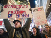 FILE - In this Thursday, Dec. 7, 2017 file photo, Demonstrators rally in support of net neutrality outside a Verizon store in New York. Consumers aren’t likely to see immediate changes following Monday, June 11, 2018 formal repeal of Obama-era internet rules that had ensured equal treatment for all. Rather, any changes are likely to happen slowly, and companies will try to make sure that consumers are on board with the moves, experts say.