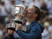 Romania's Simona Halep kisses the trophy as she celebrates winning the final match of the French Open tennis tournament against Sloane Stephens of the U.S. in three sets 3-6, 6-4, 6-1, at the Roland Garros stadium in Paris, France, Saturday, June 9, 2018.