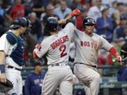 Boston Red Sox's Xander Bogaerts (2) is congratulated on his solo home run by Rafael Devers as Seattle Mariners catcher Mike Zunino stands nearby during the sixth inning of a baseball game Thursday, June 14, 2018, in Seattle.