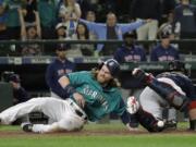 Seattle Mariners' Ben Gamel, left, scores as Boston Red Sox catcher Sandy Leon can't hold on to the ball during the eighth inning of a baseball game Friday, June 15, 2018, in Seattle. Gamel scored on a go-ahead two-run double by Denard Span. The Mariners won 7-6. (AP Photo/Ted S.