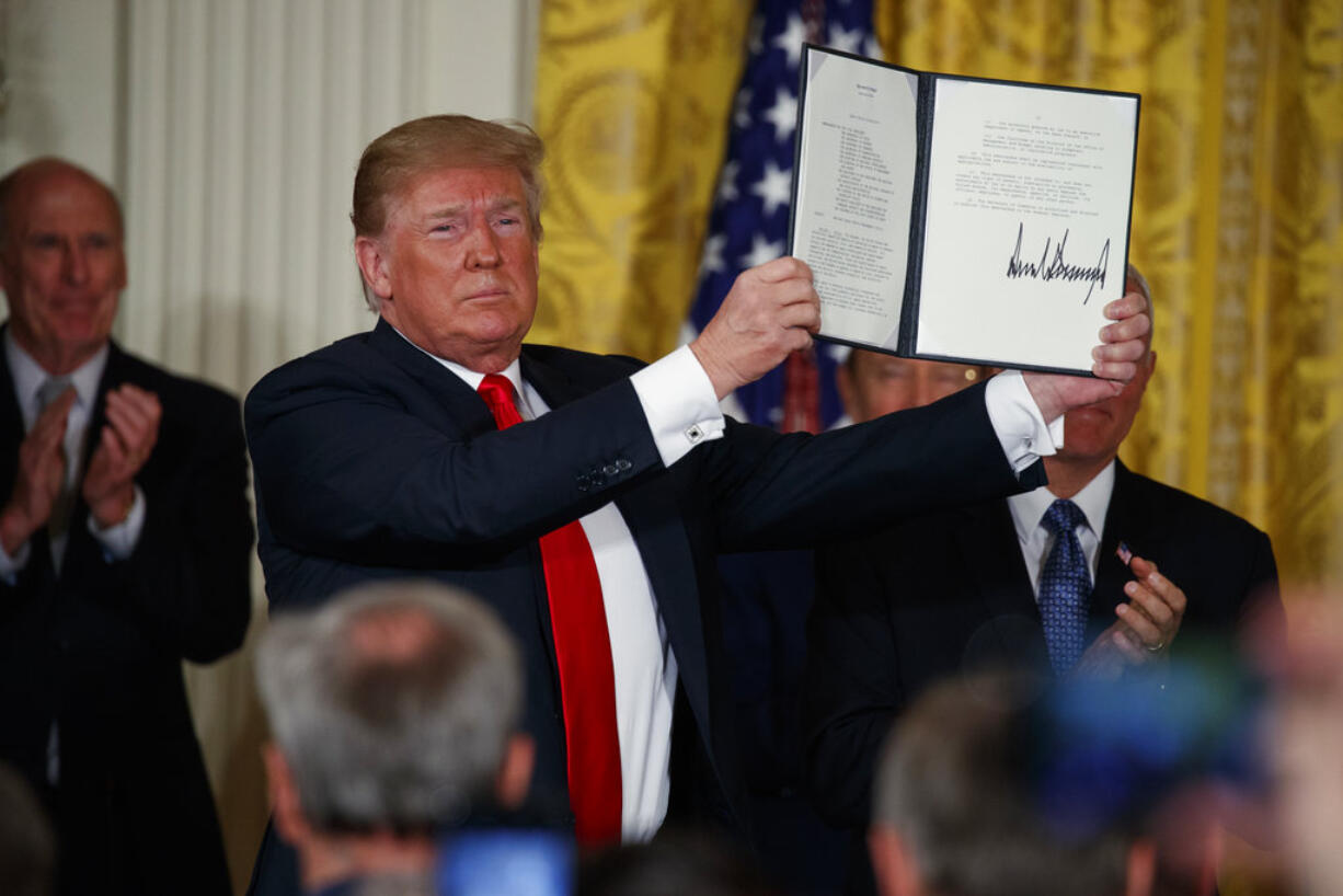 President Donald Trump shows off a "Space Policy Directive" after signing it during a meeting of the National Space Council in the East Room of the White House, Monday, June 18, 2018, in Washington.